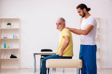 Obraz premium Old male patient visiting young male doctor chiropractor