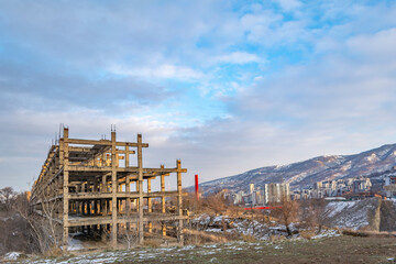 Fototapeta na wymiar Unfinished abandoned construction. Urban landscape in the rays of the sunset of the winter sun.