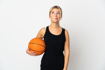 Obraz premium Young Russian woman playing basketball isolated on white background and looking up