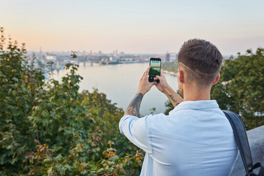 Young man taking photo on smartphone while traveling by Europe.
