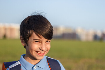 Returning to school concept, portrait of happy boy with backpack, school child waiting for school bus, primary school student, on the way to school