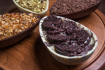 Pistachio, chocolate, hazelnut and white chocolate stuffed easter eggs on a wooden stand.