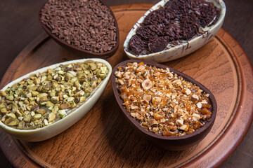 Pistachio, chocolate, hazelnut and white chocolate stuffed easter eggs on a wooden stand.