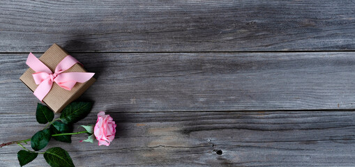 Single pink rose with gift box  over weathered wooden planks for Mothers day holiday concept background