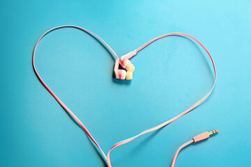 Love music concept. Pink headphones in the form of a heart on a blue background.