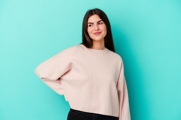 Young caucasian woman isolated on blue background dreaming of achieving goals and purposes