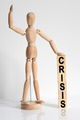 The wooden man raised his hand, and under his left hand he has cubes with the inscription -CRISIS