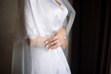 The bride in a dressing gown hugs herself.