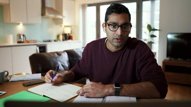 Mixed race business man working from home writing on note pad working from home office