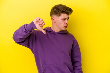 Young caucasian man isolated on yellow background showing thumb down and expressing dislike.