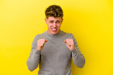 Young caucasian man isolated on yellow background upset screaming with tense hands.