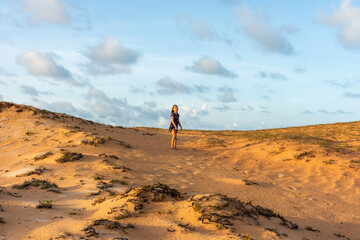 Menina solitaria em duna de areia ao entardecer