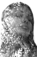 A monochrome double exposure portrait of a woman with plant leaves on white background