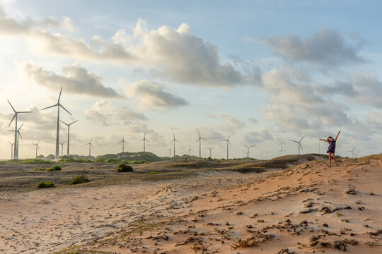 Parque e&oacute;lico isolado em deserto com crian&ccedil;a observando