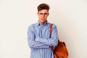 Young student man isolated on white background frowning face in displeasure, keeps arms folded.