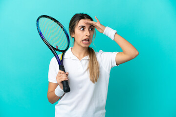 Young woman tennis player isolated on blue background doing surprise gesture while looking to the side