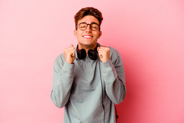 Young student man isolated on pink background raising fist, feeling happy and successful. Victory concept.