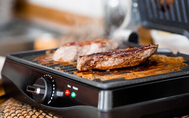 Barbecue party. Delicious beef steaks on a contact electric grill-close-up. Cooking in the home...