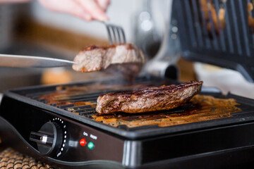 Barbecue party. Delicious beef steaks on a contact electric grill-close-up. Cooking in the home...