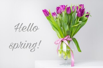 Obraz premium A bouquet of tulips in a vase. Banner hello spring . Lilac tulips. New season. Spring. Hi, Mart. Flowers in a vase.