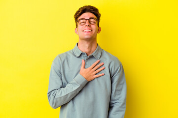 Fototapeta premium Young caucasian man isolated on yellow background laughs out loudly keeping hand on chest.