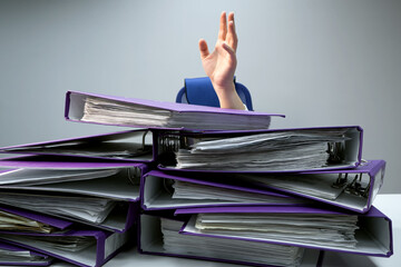 raised hands of a person who sinks behind stacks of ring binders on an office desk. concept of...