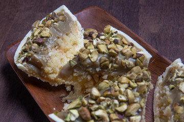 Cracked stuffed pistachio and white chocolate easter egg on a wooden stand on a wooden table.