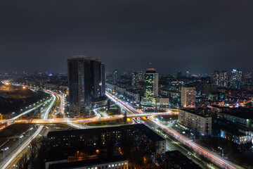 Aerial panoramic drone above roof view of Kiev night traffic road junction scene. Highway city at evening car light trails. Scenic urban skyline cityscape. Busy downtown life of Ukraine capital