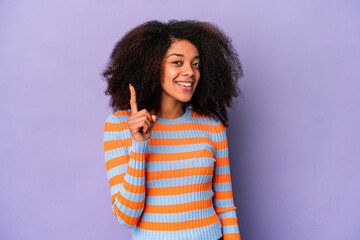 Young african american curly woman isolated on purple background showing number one with finger.