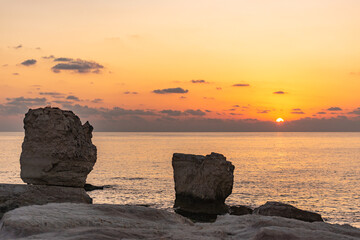 Fototapeta na wymiar Sunset draws a sunny path on the sea among the rocks.