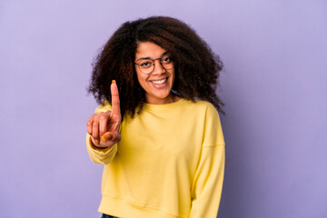 Young african american curly woman isolated on purple background showing number one with finger.