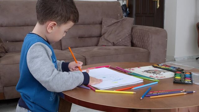 Little Boy Drawing stock video is a great piece of video that contains a little boy using colored pencils to draw a picture. 