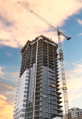 Fototapeta premium A construction crane builds a tall downtown apartment building in Calgary Alberta Canada.