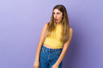 Young woman over isolated purple background doing surprise gesture while looking to the side
