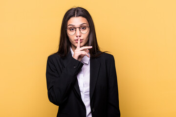 Young Indian business woman isolated on yellow background keeping a secret or asking for silence.