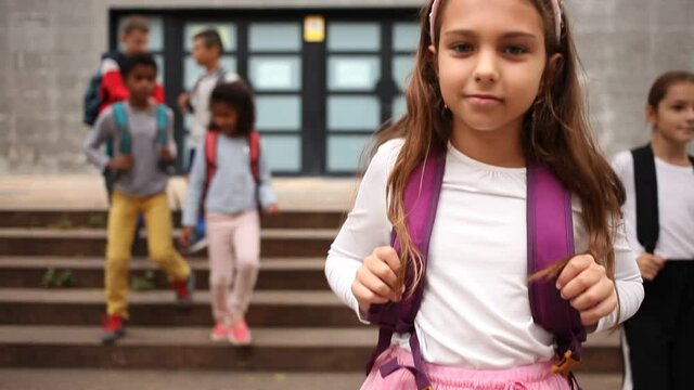 Portrait of preteen schoolchildren of different nationalities with backpacks outdoors on their way to college in warm autumn day. Back to school concept. High quality FullHD footage