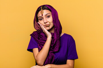 Young Indian woman wearing a traditional sari clothes isolated on yellow background who is bored, fatigued and need a relax day.