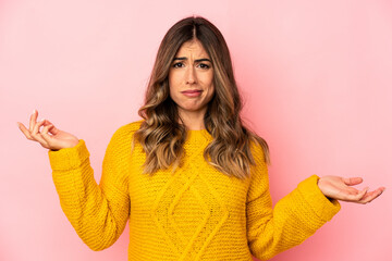 Young caucasian woman isolated doubting and shrugging shoulders in questioning gesture.