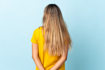 Young hispanic woman over isolated blue background in back position and looking back