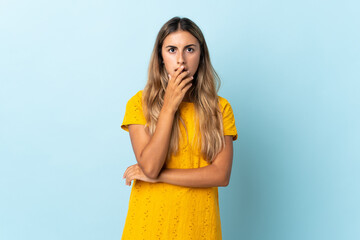 Young hispanic woman over isolated blue background surprised and shocked while looking right