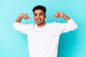 Young african american curly man isolated on blue showing strength gesture with arms, symbol of feminine power