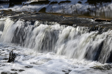 Waterfall splashing over river rocks in winter