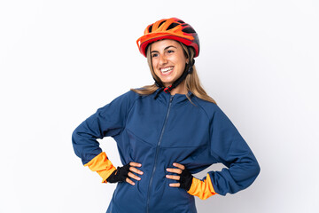 Young hispanic cyclist woman isolated on white background posing with arms at hip and smiling