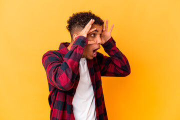 Young african american curly man isolated on purple keeping eyes opened to find a success...