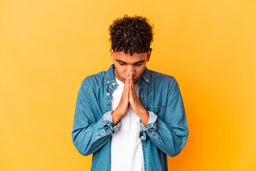 Young african american curly man isolated on purple praying, showing devotion, religious person...