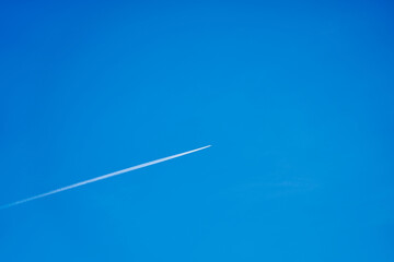 A trail from the plane in the blue clear sky.