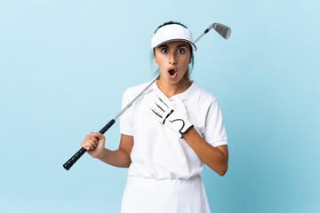 Young hispanic golfer woman over isolated blue wall surprised and shocked while looking right