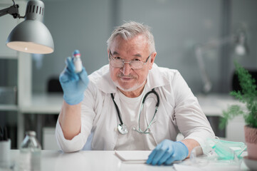 An elderly, experienced, reliable doctor demonstrates the coronavirus vaccine to the camera. The concept of vaccination of the population against covid-19.