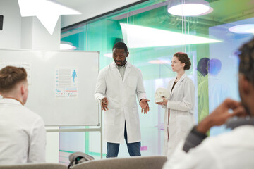 Portrait of African-American man talking to audience while giving presentation during medical seminar in college, copy space