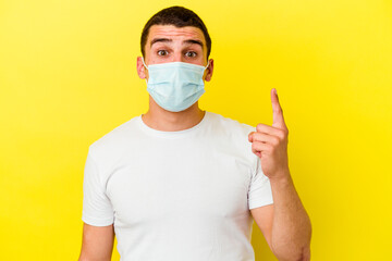 Young caucasian man wearing a protection for coronavirus isolated on yellow background having some great idea, concept of creativity.